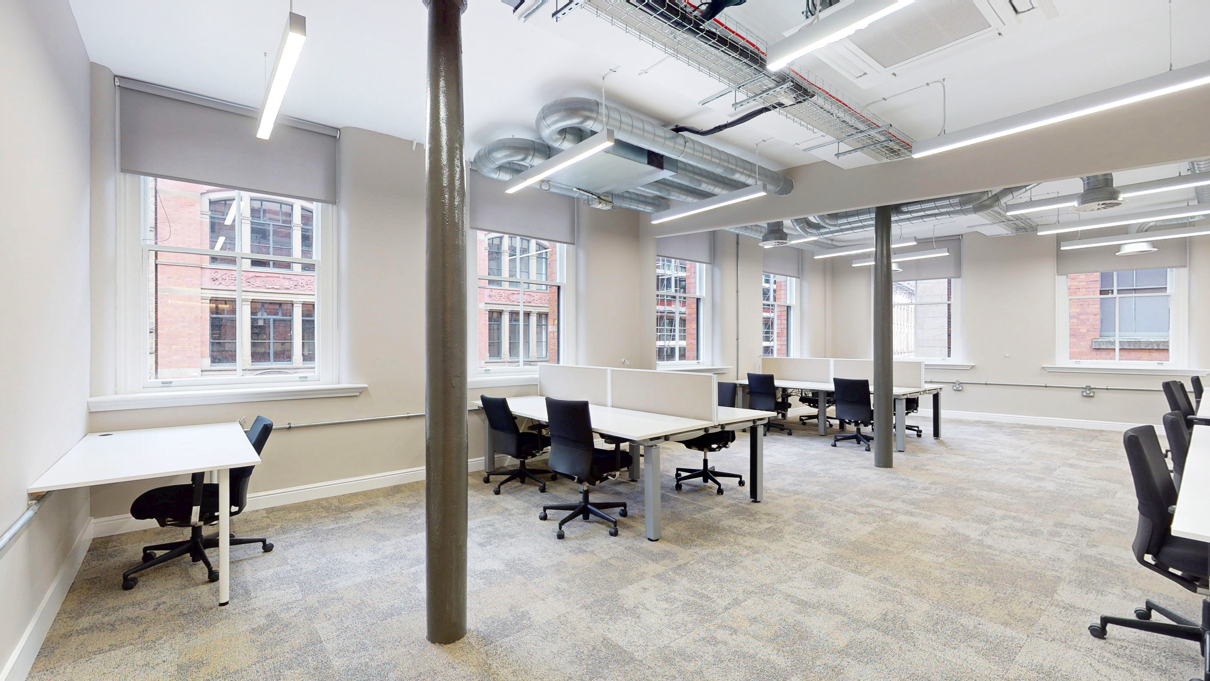 A private serviced suite at 101 Princess Street — desks, restored heritage windows and original cast-iron column